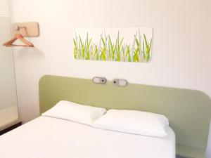 a bed with a green headboard and a picture of grass at SUN1 Durban in Durban