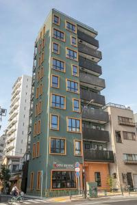 a tall green building on a city street at the Moto Hotel Asakusa in Tokyo