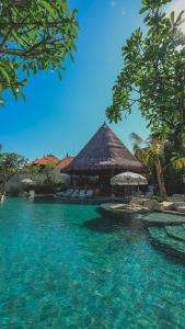 een resort met een zwembad met stoelen en een gebouw bij Amnaya Resort Nusa Dua in Nusa Dua