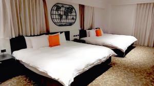 two beds in a room with white and orange pillows at Fulidun Hotel Kenting in Hengchun South Gate