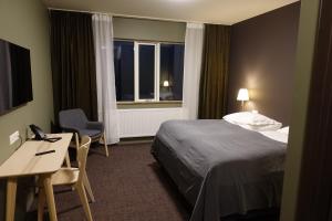 a hotel room with a bed and a desk and a window at Basalt Hotel in Borgarnes