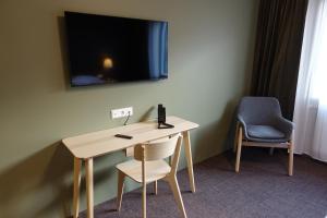 a desk with a chair and a television on a wall at Basalt Hotel in Borgarnes