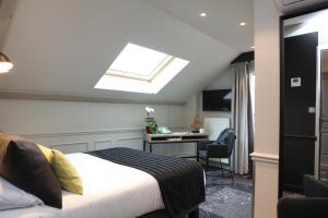 a bedroom with a bed and a desk and a skylight at Allobroges Park Hôtel in Annecy