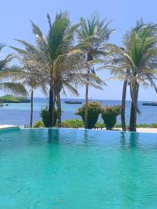 uma piscina com palmeiras e o oceano em Lily Palm Resort em Watamu