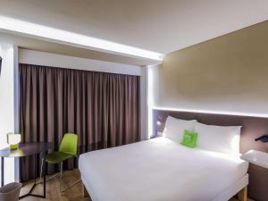 a hotel room with a large white bed and a desk at Ibis Styles Lisboa Centro Marquês de Pombal in Lisbon