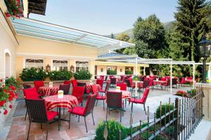 a restaurant with red chairs and tables on a patio at Hotel Bräu in Zell am Ziller