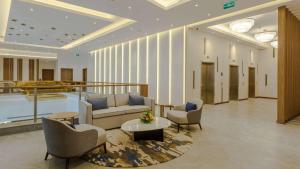 eine Lobby mit einem Sofa, Stühlen und einem Tisch in der Unterkunft Clarion Hotel Jeddah Airport in Dschidda