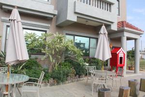 two tables and chairs with umbrellas in front of a building at 八八小屋心享民宿 in Jinning