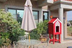 a table with an umbrella and a bird house at 八八小屋心享民宿 in Jinning