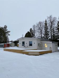 une grande maison blanche avec une cour recouverte de neige dans l'établissement Modern Lapland Cottage with Outdoor Sauna & BBQ Hut, à Slagnäs