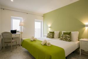 a bedroom with a large bed with a green blanket at Suites Amália Guesthouse near Rossio Square in Lisbon