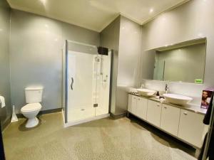 een badkamer met een toilet, 2 wastafels en een douche bij Gamma Hotel in Auckland