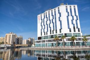 ドバイにあるIntercityHotel Dubai Jaddaf Waterfrontの水の前のヤシの木の建物