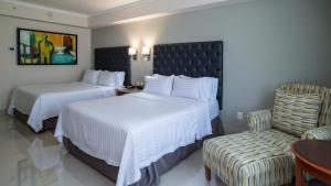 a hotel room with two beds and a chair at Holiday Inn Tuxtla Gutierrez, an IHG Hotel in Tuxtla Gutiérrez