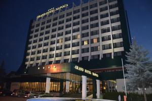 a hotel building with a parking lot in front of it at Grand Hotel Napoca in Cluj-Napoca