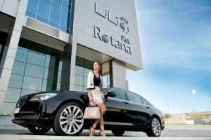 uma mulher ao lado de um carro preto em frente a um edifício em Park Rotana Abu Dhabi em Abu Dhabi