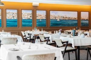 un restaurant avec des tables blanches, des chaises et des fenêtres dans l'établissement Corpo Santo Lisbon Historical Hotel, à Lisbonne