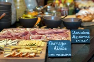 a table topped with cheese and meats and other foods at Hôtel Tandem - Boutique Hôtel in Strasbourg