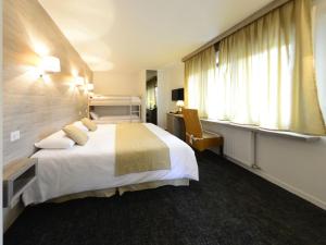 a hotel room with a bed and a desk and windows at Hotel Les Terrasses in Annecy