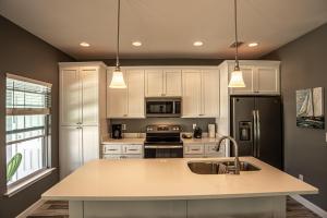 a kitchen with white cabinets and a black refrigerator at Beach Daze in Panama City Beach