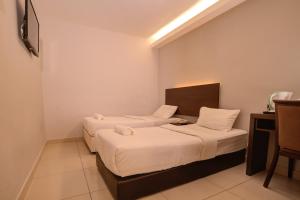 two beds in a small room with a table and chairs at GM Metro at Sunway in Petaling Jaya