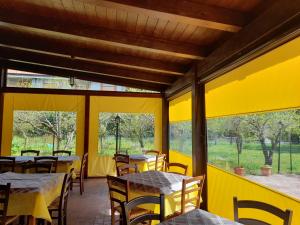 a yellow restaurant with tables and chairs and windows at Hotel Edelweiss in Laino Borgo