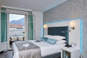 ein Hotelzimmer mit einem Bett und einem großen Fenster in der Unterkunft Best Western Plus Hotel Carlton Annecy in Annecy