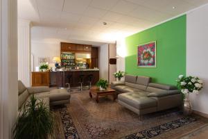 a living room with couches and a green wall at Hotel Dei Tigli in Angera