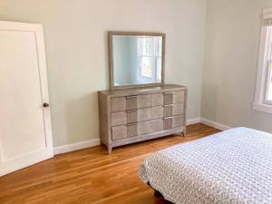 a bedroom with a dresser with a mirror and a bed at University House - 8 Bedrooms Walk to UF / Stadium in Gainesville