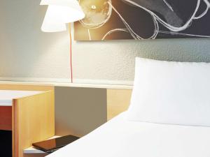 um quarto com uma cama e uma secretária com um candeeiro em ibis Strasbourg Centre Historique em Estrasburgo