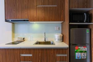 a kitchen with a sink and a microwave and a refrigerator at Aurora Serviced Apartments in Ho Chi Minh City