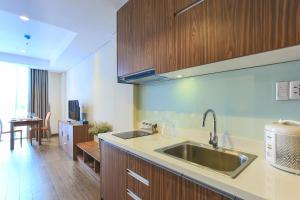 a kitchen with a stainless steel sink and wooden cabinets at Aurora Serviced Apartments in Ho Chi Minh City