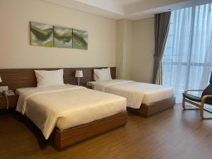 a hotel room with two beds and a window at Aurora Serviced Apartments in Ho Chi Minh City