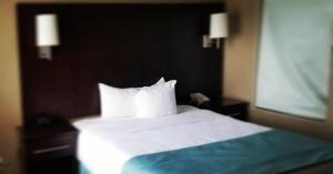 um quarto com uma cama com lençóis brancos e almofadas em Comfort Inn & Conference Centre Toronto Airport em Toronto