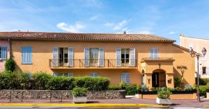 ein gelbes Haus mit Balkon auf einer Straße in der Unterkunft Hôtel Le Y in Saint-Tropez