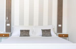 a large white bed with two pillows on it at Midenza Seaside & Nature Retreat in Capo Vaticano