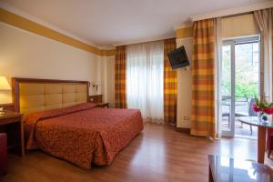 a hotel room with a bed and a television at Hotel Il Chiostro by LVG Hotel Collection in Verbania