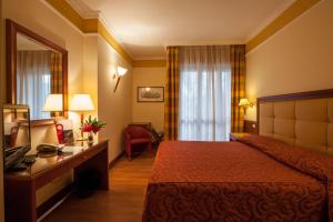 a hotel room with a bed and a desk and a television at Hotel Il Chiostro by LVG Hotel Collection in Verbania