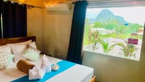 Schlafzimmer mit einem Bett und einem großen Fenster in der Unterkunft Hidden of Cailan Inn in El Nido