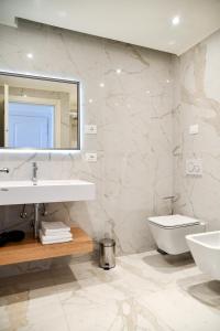 a white bathroom with a sink and a toilet at Sempione Boutique Hotel in Stresa