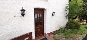 un edificio blanco con una puerta marrón y dos luces en Gemütliches Ferienhaus "An der Schilde" in Renzow, en Renzow