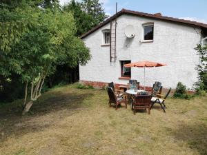 una mesa con sillas y una sombrilla frente a una casa en Gemütliches Ferienhaus "An der Schilde" in Renzow, en Renzow