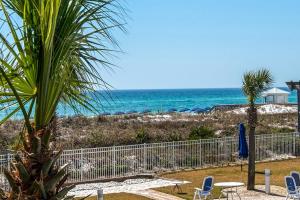 a beach with chairs and a fence and the ocean at Destin West Gulfside #203 in Fort Walton Beach