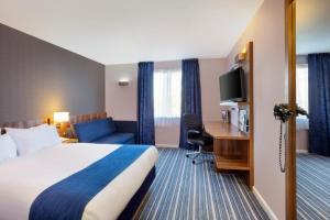 Holiday Inn Express Poole, an IHG Hotel في بول: غرفة في الفندق مع سرير ومكتب