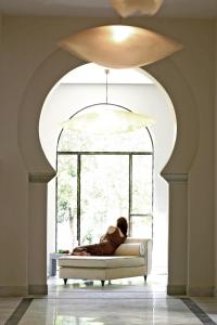 una persona sentada en un sofá frente a una ventana en Hospes Palacio del Bailio, a Member of Design Hotels, en Córdoba