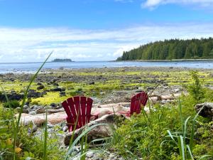 two red chairs sitting on a beach near the water at So Damn Lucky Glamping in Ucluelet