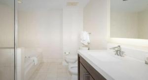 a white bathroom with a tub and a toilet and a sink at Best Resort Beach Front Condo in Miami Beach