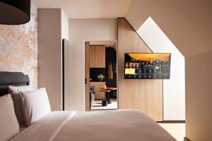 a bedroom with a white bed and a kitchen at Hôtel LÉONOR the place to live in Strasbourg