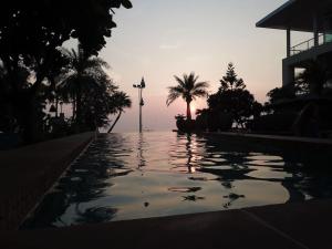 uma piscina com um pôr-do-sol ao fundo em Karon Sea View Beach Apartment em Praia de Karon