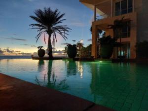 uma piscina em frente a um edifício com uma palmeira em Karon Sea View Beach Apartment em Praia de Karon